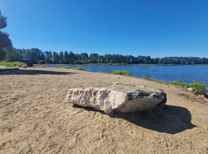 Iso kivi hiekkarannalla järvimaisemassa